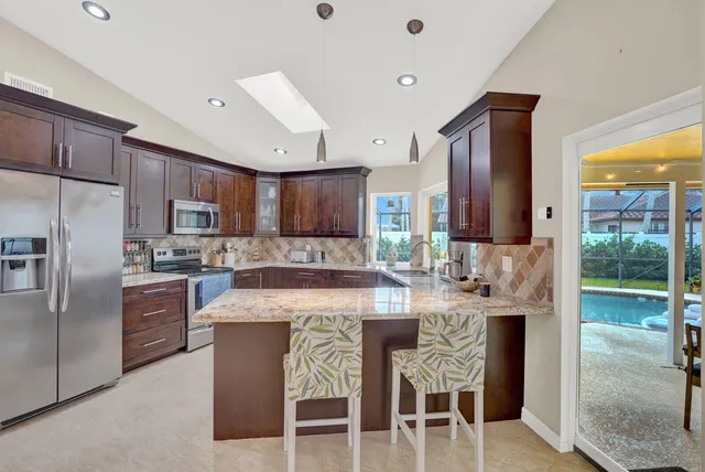 a kitchen with stainless steel appliances granite countertop a stove a refrigerator a oven a sink with a dining table and chairs