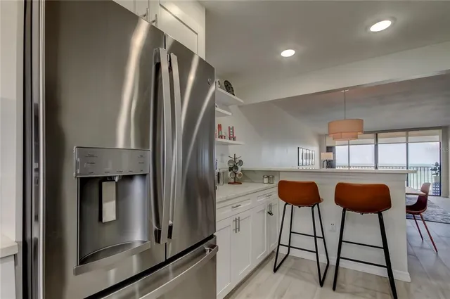 a kitchen with stainless steel appliances kitchen island granite countertop a refrigerator and a sink