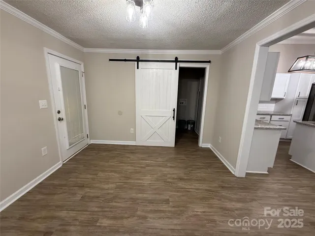 a view of an empty room with wooden floor and a bathroom