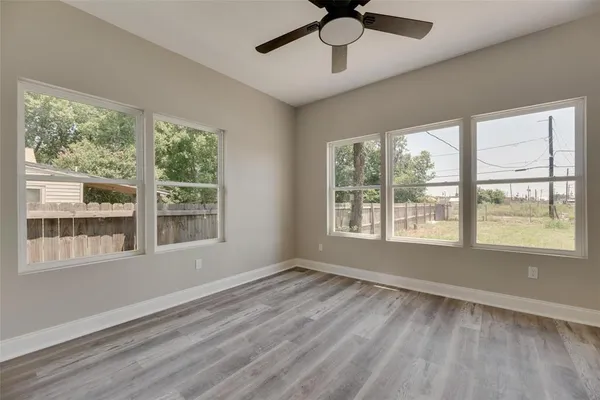 a view of an empty room with wooden floor and a window