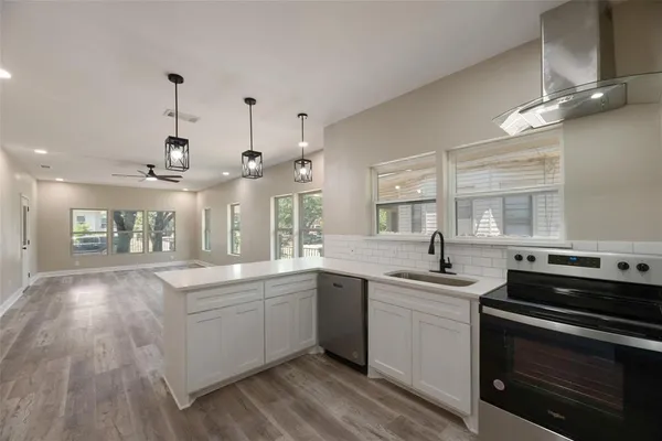 a large white kitchen with a stove top oven a sink dishwasher and a stove with wooden floor