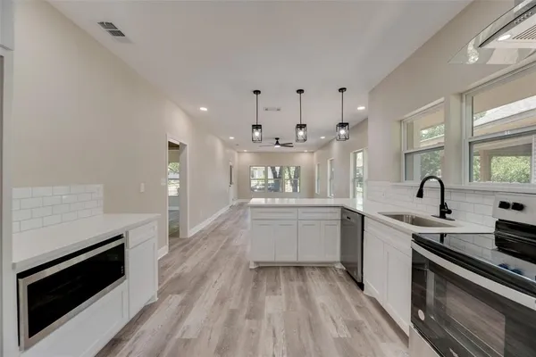 a large white kitchen with kitchen island white cabinets and stainless steel appliances