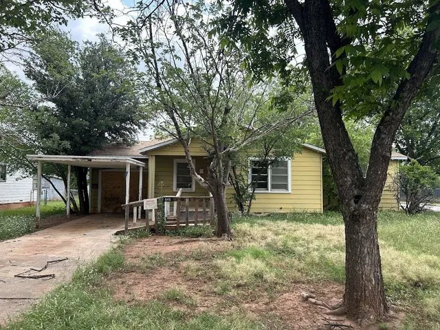 front view of a house with a yard and an trees