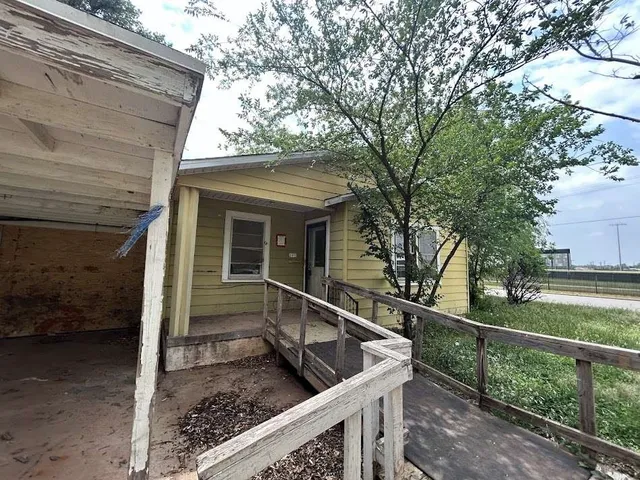 a view of house with wooden deck and a large tree