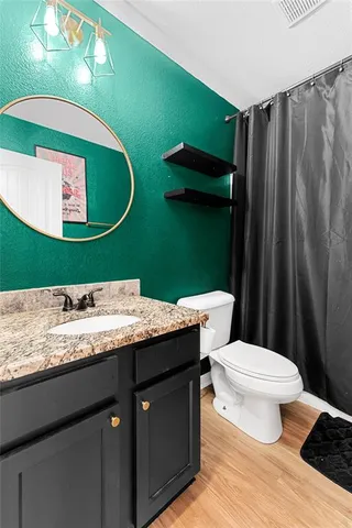 a bathroom with a granite countertop toilet sink and mirror
