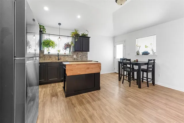 a kitchen with stainless steel appliances a dining table chairs and wooden floor