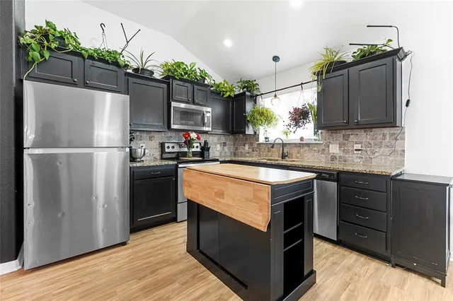 a kitchen with kitchen island granite countertop a sink stove and refrigerator