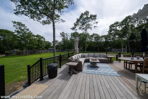 a view of a deck with couches table and chairs with wooden floor and fence