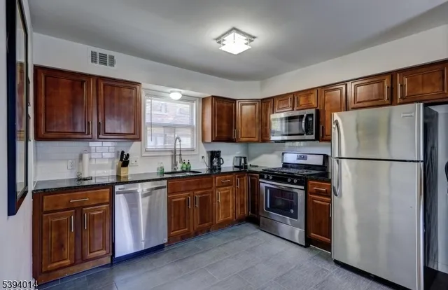 a kitchen with stainless steel appliances granite countertop a refrigerator stove a sink dishwasher and microwave