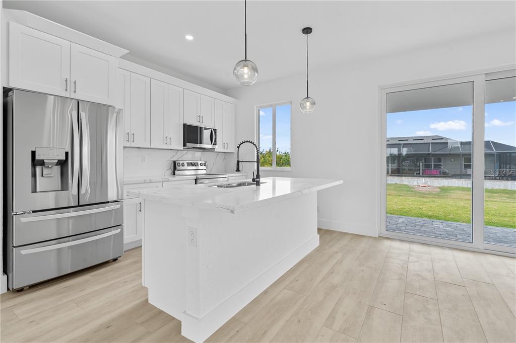 13438 Mc Intosh Avenue Port Charlotte, FL 33981 - Photo 14 of 46 a kitchen with kitchen island a stove a refrigerator a sink and a oven with wooden floor