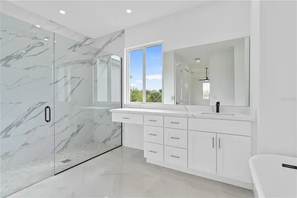 a spacious bathroom with a granite countertop sink a mirror a bathtub and a shower