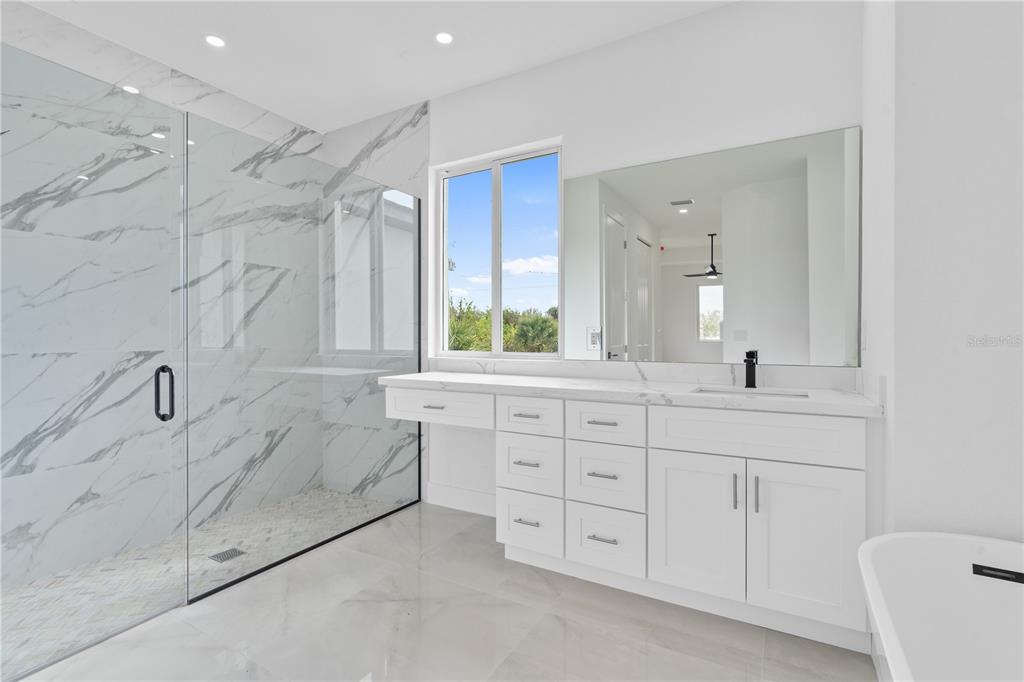 13438 Mc Intosh Avenue Port Charlotte, FL 33981 - Photo 24 of 46 a spacious bathroom with a granite countertop sink a mirror a bathtub and a shower
