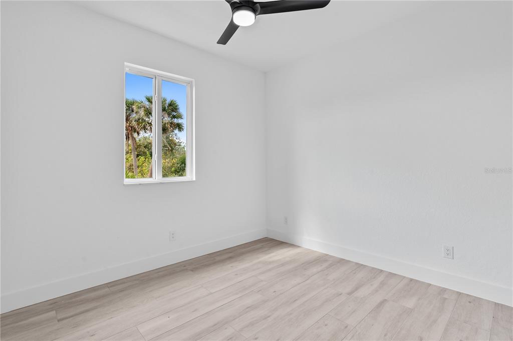 13438 Mc Intosh Avenue Port Charlotte, FL 33981 - Photo 32 of 46 an empty room with a window and wooden floor