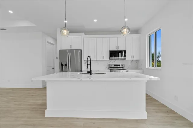 a view of kitchen with microwave a refrigerator and a stove top oven with wooden floor