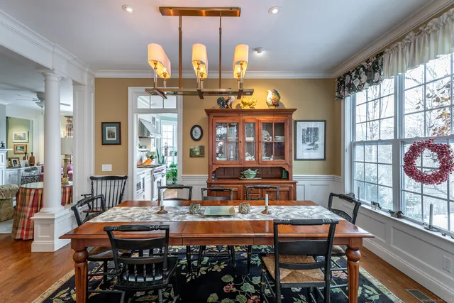 a dining room with chandelier and wooden floor