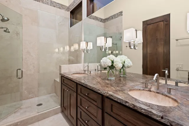 a bathroom with a granite countertop double vanity and a mirror