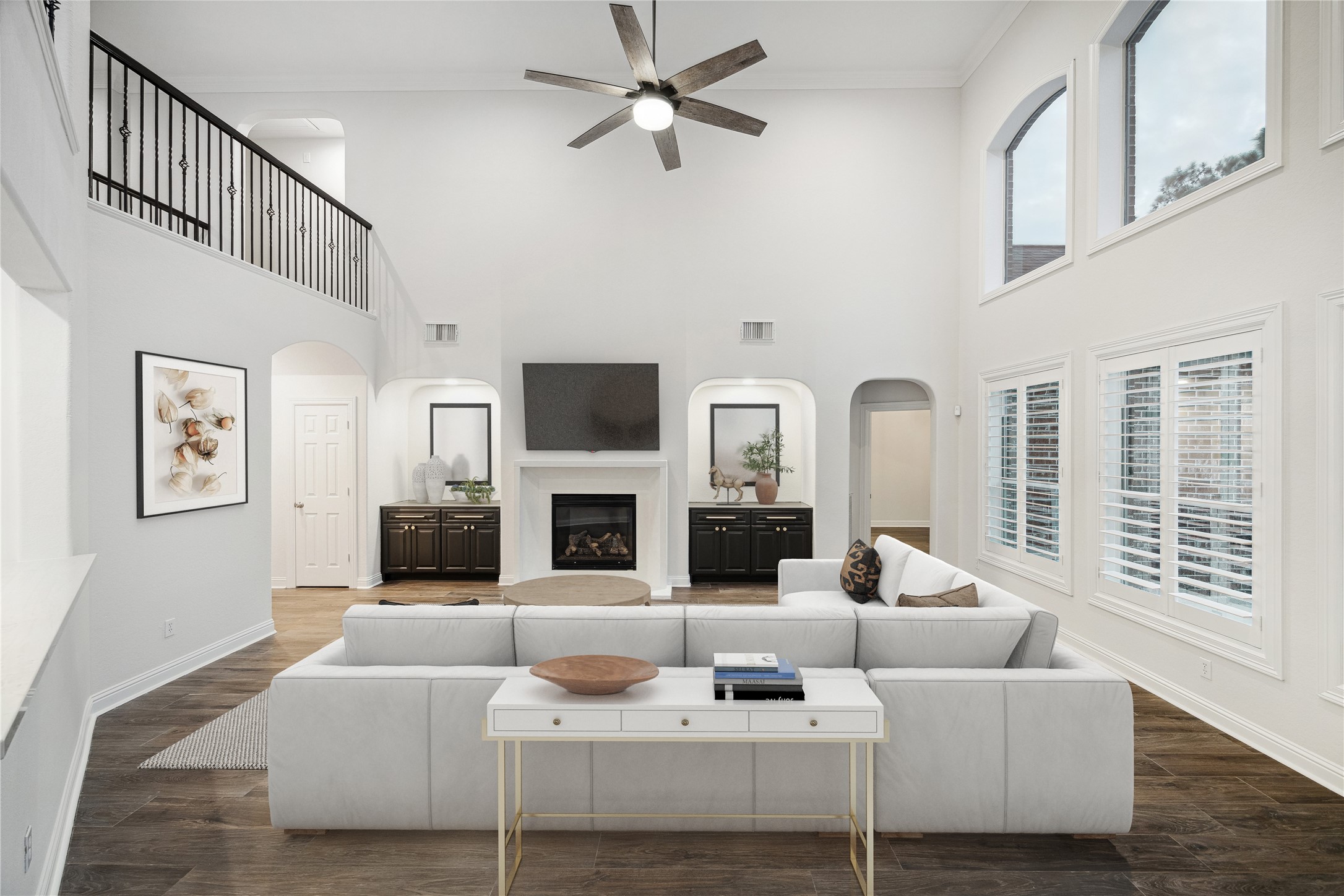 6211 Alameda Point Lane Houston, TX 77041 - Photo 19 of 50 Dramatic two-story family room featuring soaring ceilings, elegant fireplace flanked by built-in arched niches, plantation shutters, and an open iron balcony railing above. *Photo has been virtually staged.
