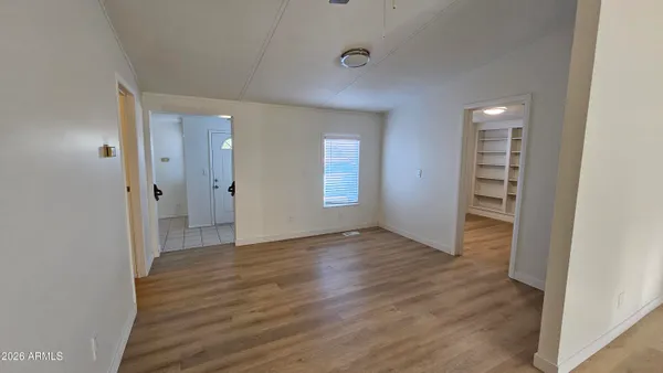 a view of an empty room with wooden floor and a window
