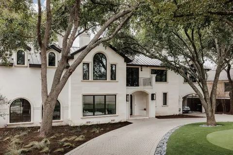 a view of a white house with a large tree