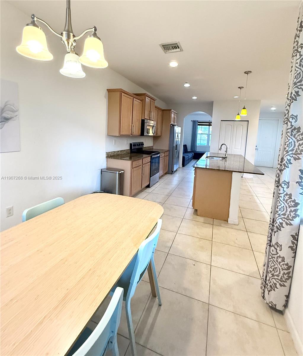 1740 Northwest 21st Street Homestead, FL 33030 - Photo 13 of 23 a large kitchen with kitchen island granite countertop a sink a stove a dining table and chairs