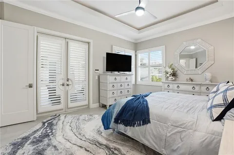 a spacious bedroom with a bed a flat screen tv and a chandelier