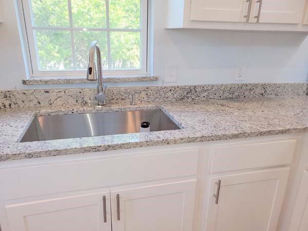 209 Campus Street Ferris, TX 75125 - Photo 22 of 33 a kitchen with granite countertop a sink window and cabinets