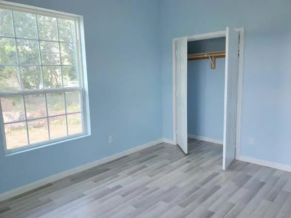 an empty room with wooden floor and windows