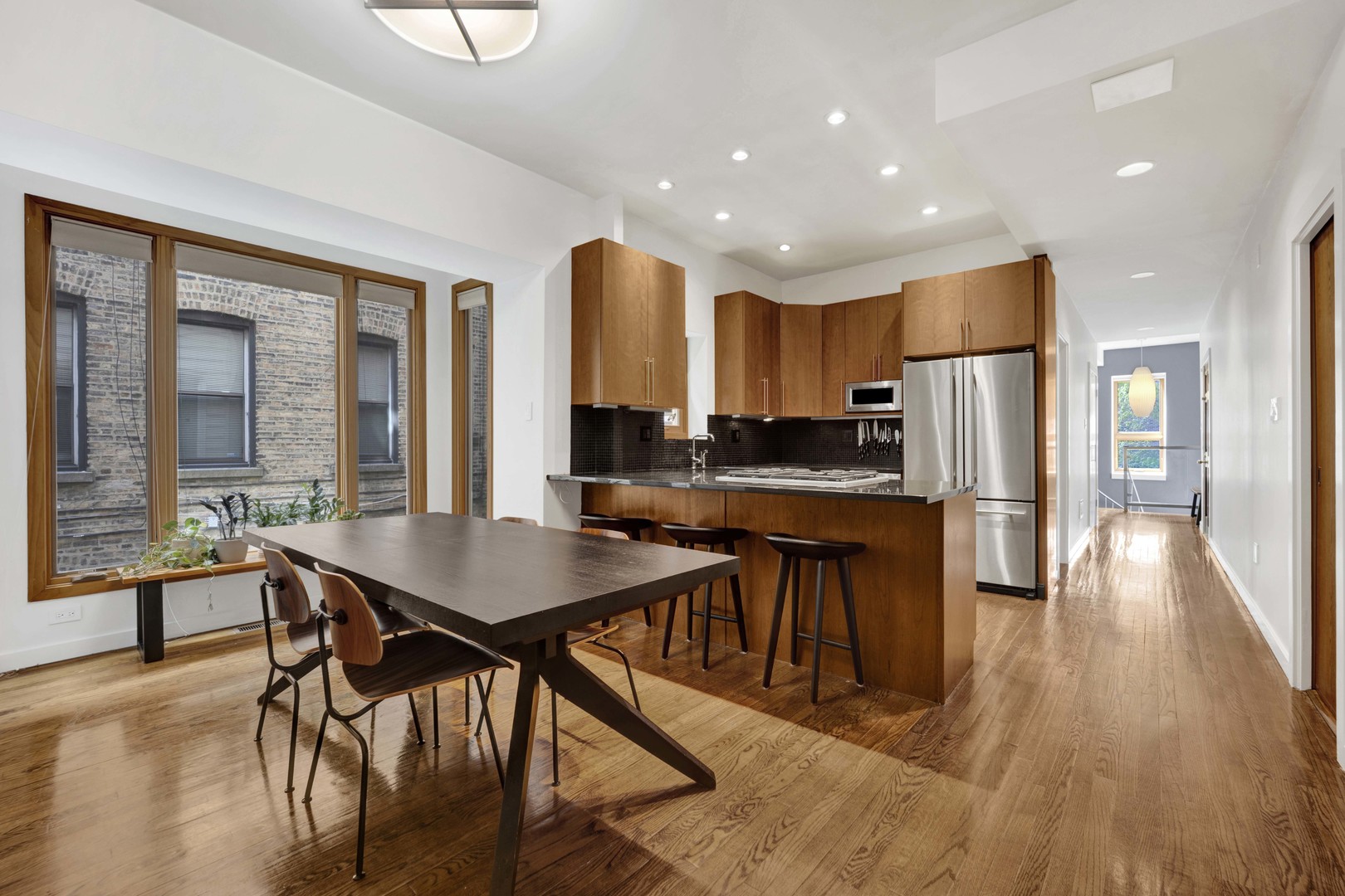 634 West Grace Street, Unit 1E Chicago, IL 60613 - Photo 4 of 26 a kitchen with stainless steel appliances granite countertop a stove a refrigerator a sink a dining table and chairs with wooden floor