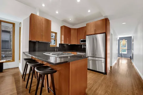a kitchen with stainless steel appliances granite countertop a refrigerator a stove a sink dishwasher and a stove with wooden floor