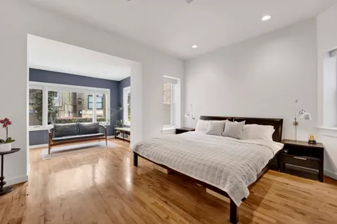 a spacious bedroom with a bed and wooden floor