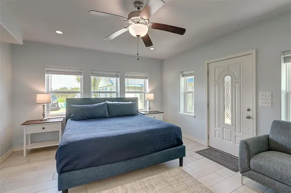 a bedroom with a large bed couch and windows