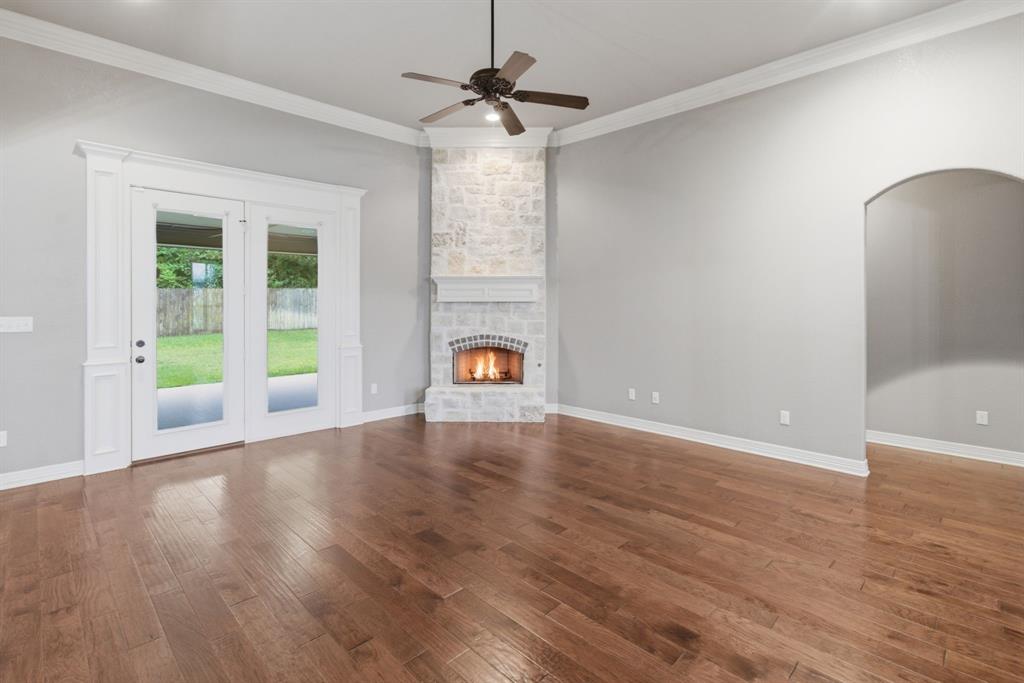 7765 Hickory Spring Lane Tyler, TX 75703 - Photo 12 of 38 Living area featuring wood-finish flooring, a stone-clad fireplace with a decorative mantel, and a ceiling fan