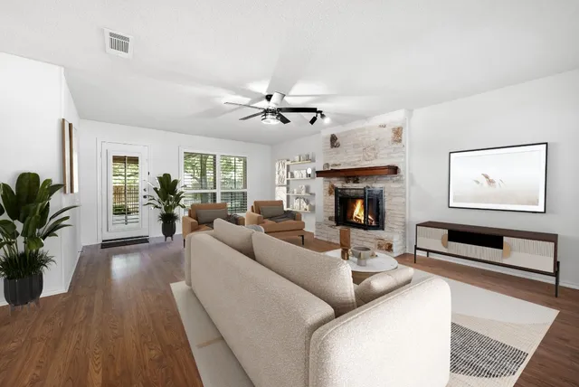 a living room with furniture a fireplace and a ceiling fan
