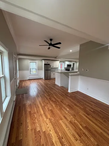 a view of a living room with wooden floor and a ceiling fan