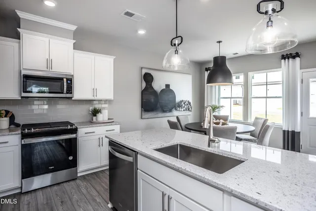 a kitchen with granite countertop a sink a counter space appliances and cabinets
