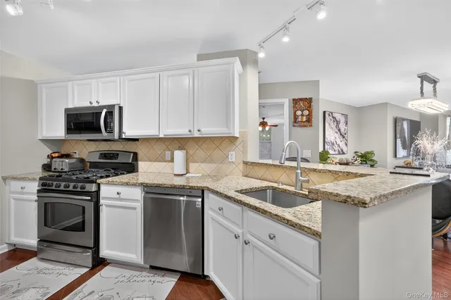 a kitchen with granite countertop a sink stainless steel appliances and white cabinets