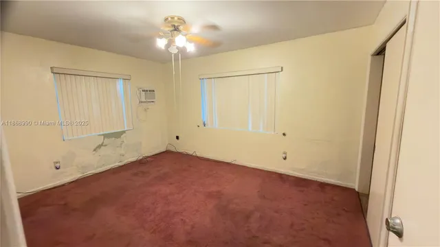 an empty room with a chandelier fan and windows