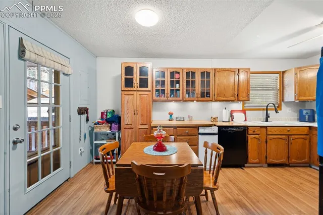 a kitchen with stainless steel appliances granite countertop a stove a sink dishwasher and a dining table with wooden floor
