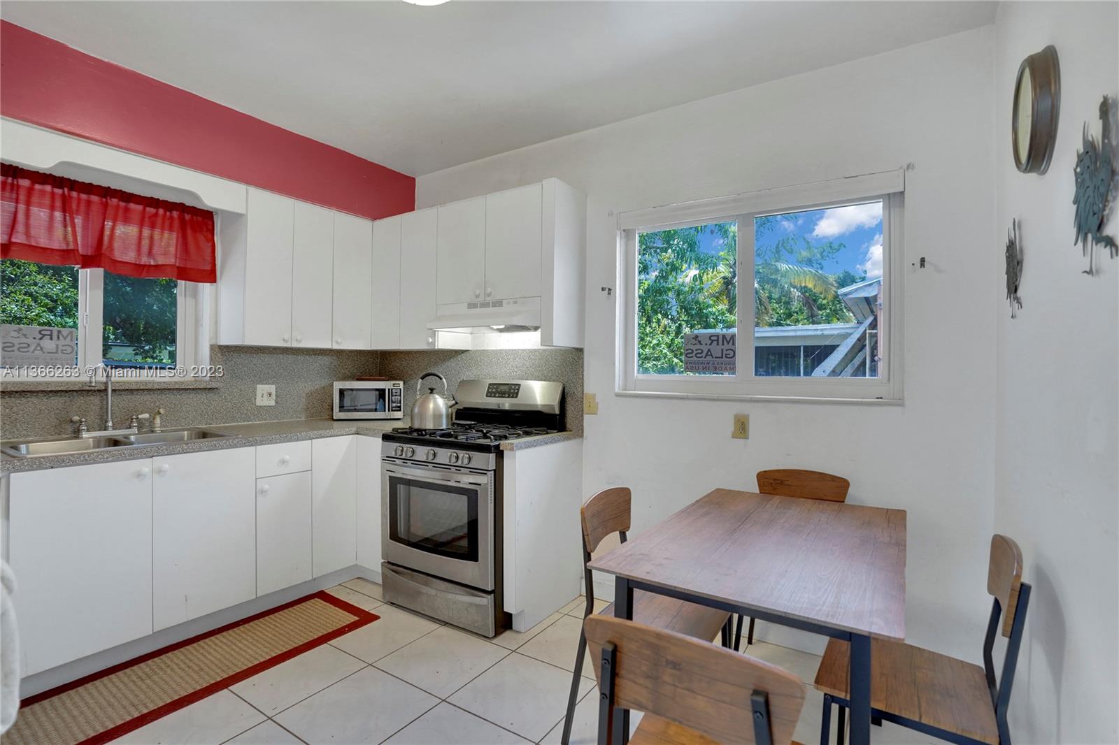 300 Northeast 48th Street Miami, FL 33137 - Photo 4 of 31 a kitchen with a stove a sink white cabinets a dining table and chairs with wooden floor