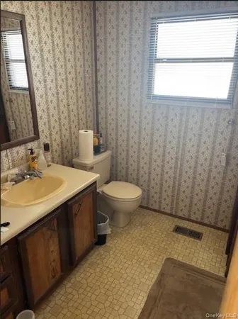 a bathroom with a granite countertop sink toilet and mirror