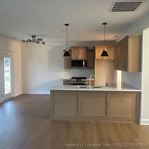 a kitchen with stainless steel appliances granite countertop a sink a stove and a wooden floors