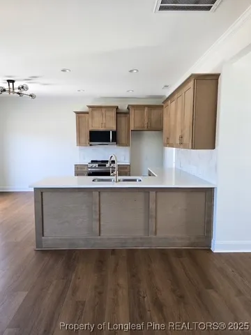 a kitchen with kitchen island granite countertop a sink and a stove top oven
