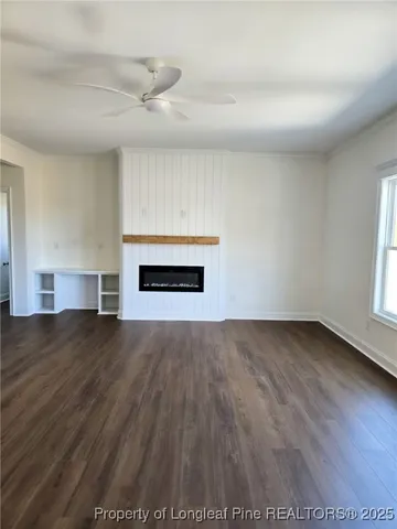 an empty room with wooden floor fireplace and windows
