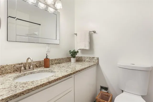 a bathroom with a granite countertop sink a toilet and mirror