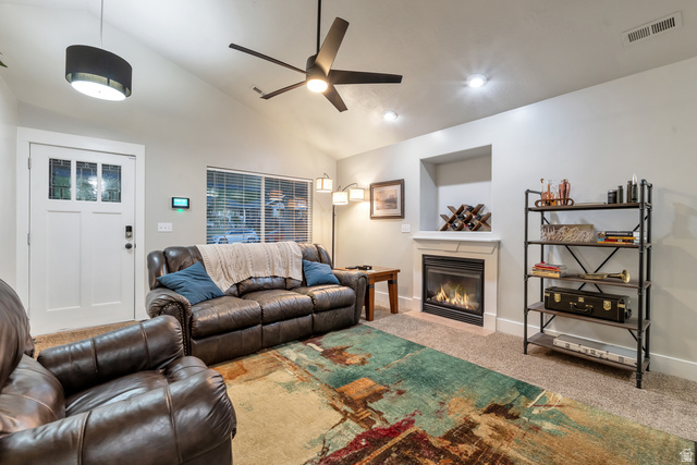 Undisclosed Address Ogden, UT 84403 - Photo 13 of 21 Living room with light carpet, a glass covered fireplace, vaulted ceiling, and ceiling fan