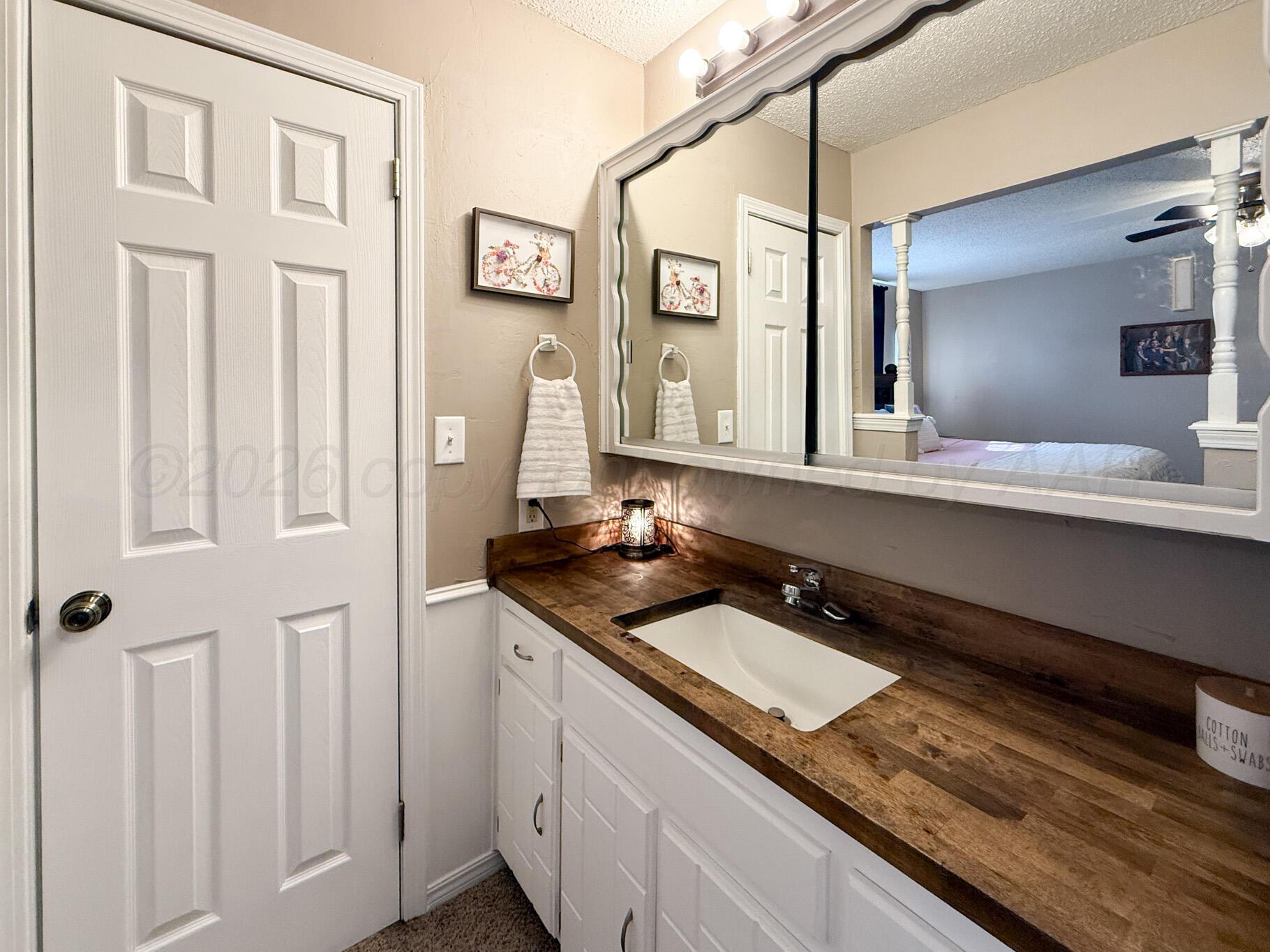 6114 Cornell Street Amarillo, TX 79109 - Photo 19 of 33 a bathroom with a granite countertop sink a mirror and a shower