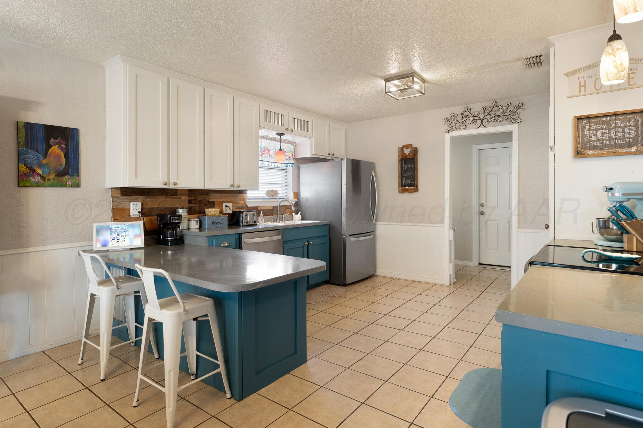 6114 Cornell Street Amarillo, TX 79109 - Photo 10 of 33 a kitchen with stainless steel appliances granite countertop a refrigerator a sink a stove and island