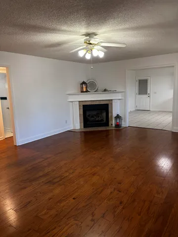 an empty room with chandelier fan and windows
