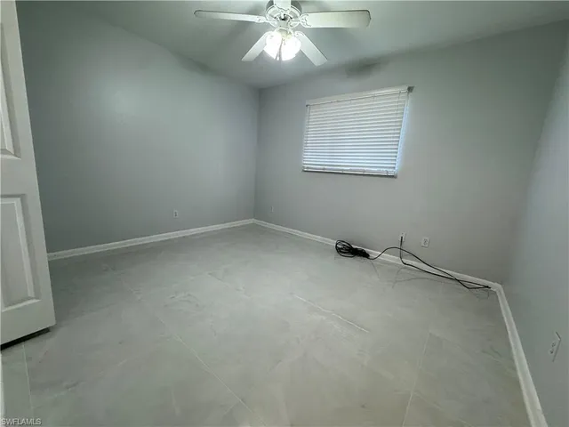 an empty room with a window and a fan