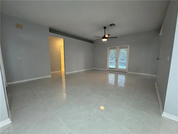 an empty room with windows and ceiling fan